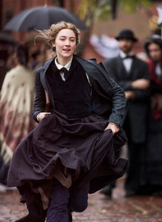 a woman dressed in period clothing running down the street