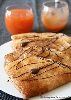 three pieces of toast on a white plate with syrup and orange juice in the background