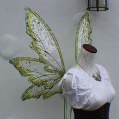 a mannequin wearing a white dress with green wings