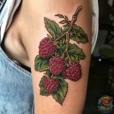 raspberry tattoo on the right arm and shoulder, with green leaves around it