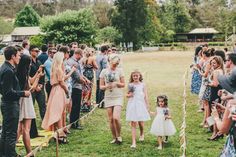 a group of people standing around each other in front of a bunch of people on the grass