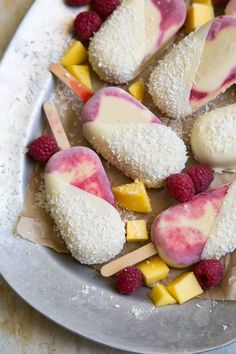 several desserts are arranged on a plate with popsicles and raspberries