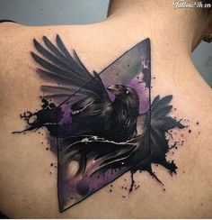 the back of a woman's shoulder with a black bird and purple paint splattered on it