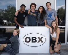 a group of young people posing for a photo in front of an obx sign