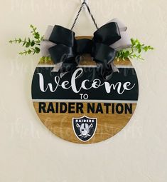 a sign that says welcome to the oakland football team hanging on a wall with greenery