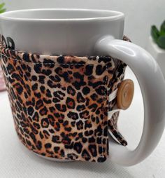 a leopard print coffee cup holder with a button on the side and a white handle