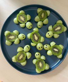 sliced kiwis arranged in the shape of faces on a blue plate