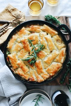 a pot pie sitting on top of a wooden cutting board next to plates and utensils