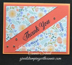 a thank card with an orange ribbon and flowers on the bottom, in front of a black background