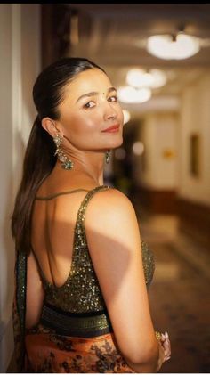 a woman in a dress standing next to a wall and looking off into the distance