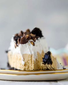 a piece of cake with white frosting and chocolate chips on top, sitting on a plate