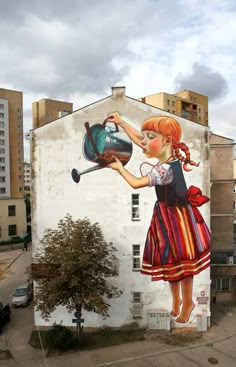 a painting on the side of a building with a girl holding a pot and a frying pan