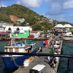 several boats are docked in the water near some houses and buildings on a hill side