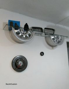 there is a clock on the wall with wheels hanging from it's sides and an air vent