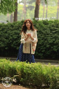 a woman standing in front of some bushes