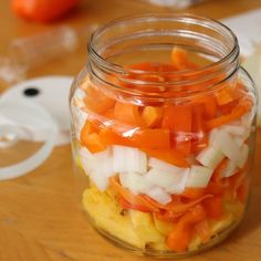 a glass jar filled with sliced vegetables on top of a wooden table