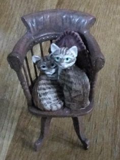 two cats are sitting in a miniature chair