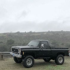 a black truck parked on top of a grass covered field