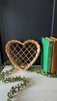 a heart shaped basket sitting on top of a table next to two green bookends