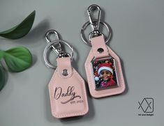 two pink leather keychains with a photo on them