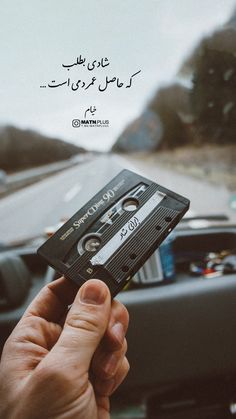 someone is holding up an old fashioned cassette in their hand while driving down the road