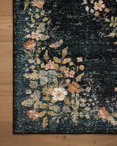 an area rug with flowers and leaves on the floor in front of a wooden surface