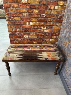 a bench sitting next to a brick wall in front of a door with a rug on it