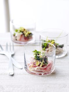 three small glass bowls with food in them on a table next to utensils