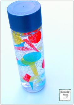 a glass cup with blue lid and colorful designs on the outside, sitting on a white surface