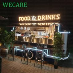 the front of a restaurant with neon lights on it's side and chairs outside