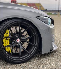 the front end of a grey car with yellow brake pads on it's tires