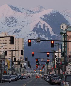 a city street with traffic lights and snow covered mountains in the backgrouds