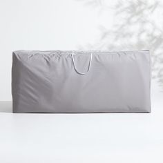 a large gray bag sitting on top of a white table next to a plant in the background