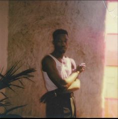 a man standing in front of a wall with his arms crossed and looking at the camera