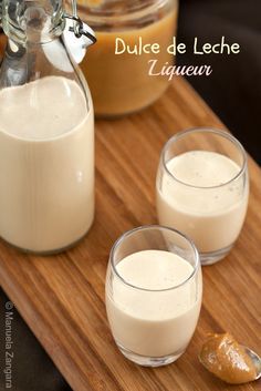 two glasses filled with milk sit on a cutting board