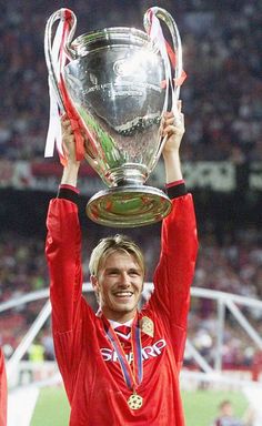 a man holding up a trophy on top of a soccer field