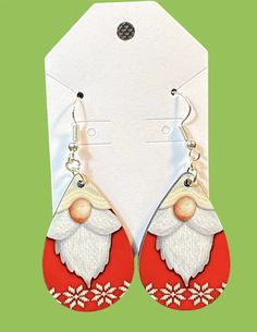 a pair of red and white santa claus earrings on a green background with an ornament