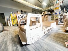 a cardboard truck bed sitting on top of a wooden floor next to stacks of boxes