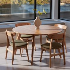 a wooden table with four chairs around it and a vase on top of the table