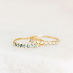 two gold rings with blue and white stones on the side, sitting on a white surface