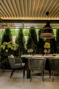 an outdoor dining area with wicker chairs and table surrounded by greenery on the walls