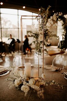 an elegant centerpiece with flowers and candles is displayed on a table in front of people