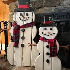 two snowmen are standing next to each other in front of a fireplace with red and black plaid scarfs