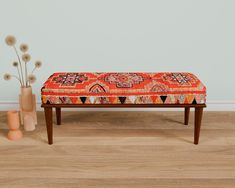 a bench with a colorful cushion on it next to some vases and a plant