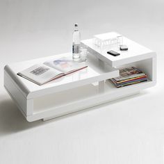 a white coffee table with magazines on it and a drink bottle in the bottom drawer