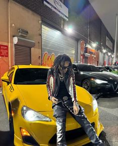 a man sitting on top of a yellow sports car