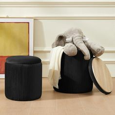 an elephant stuffed animal sitting on top of a black basket next to two round stools