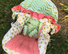 a baby's car seat covered in blankets and polka dot fabric on the grass