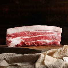 a piece of raw meat sitting on top of a wooden table next to a cloth