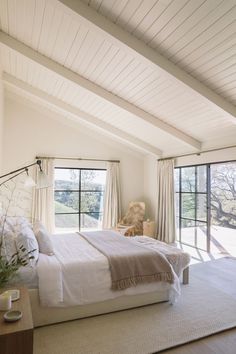 a bedroom with a large bed sitting next to two windows on each side of the room